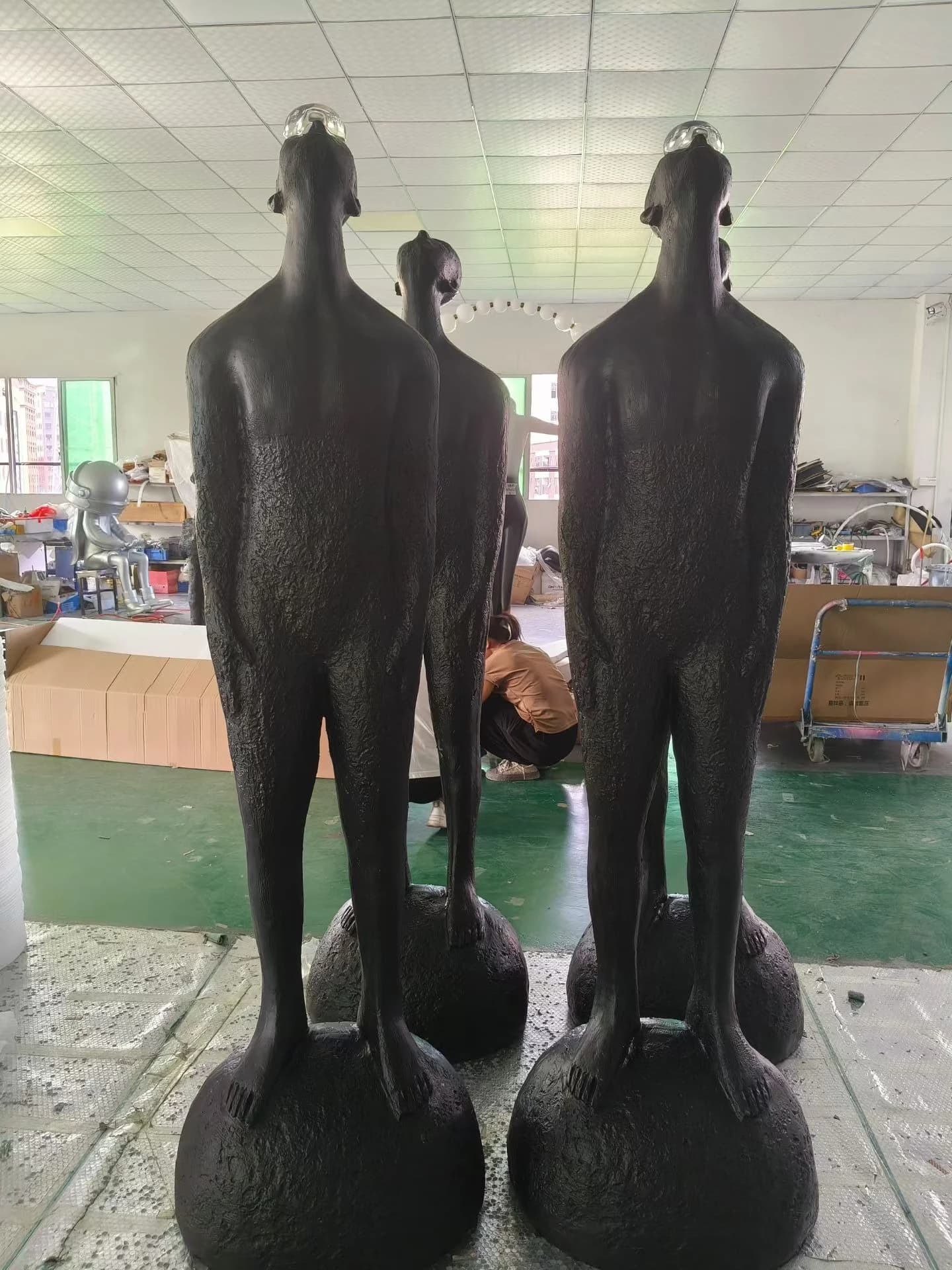 Escultura de figura alta de pie sobre esfera