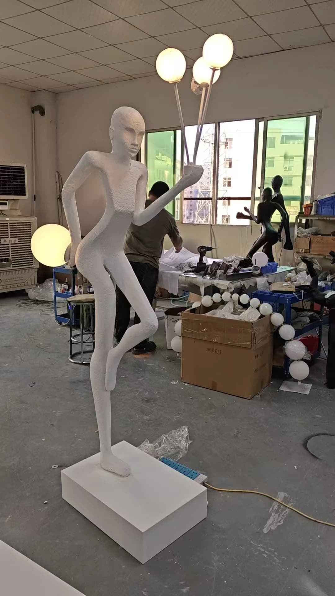 Escultura de figura blanca con ramo de globos de luz