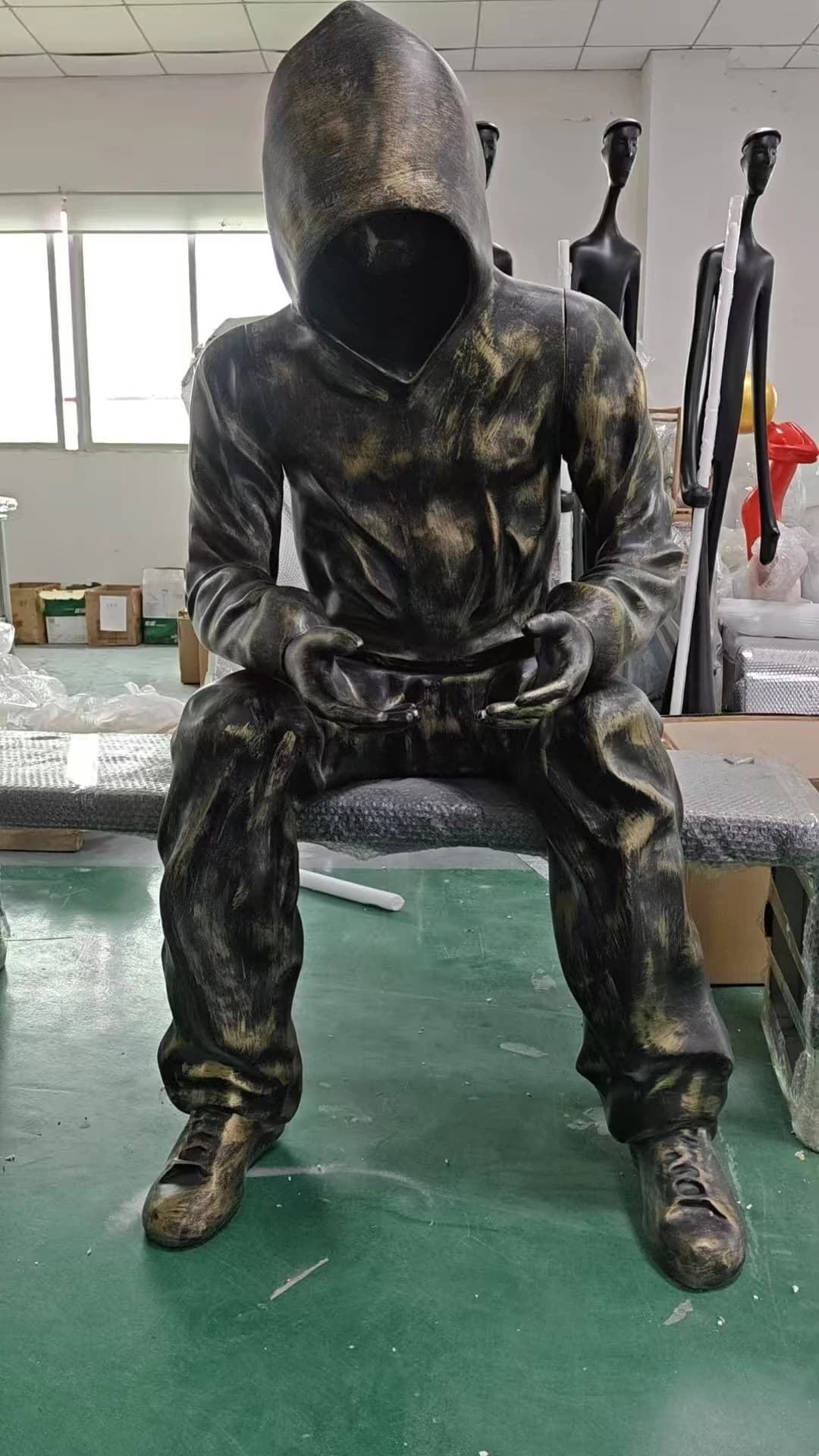 Escultura de figura sentada con capucha