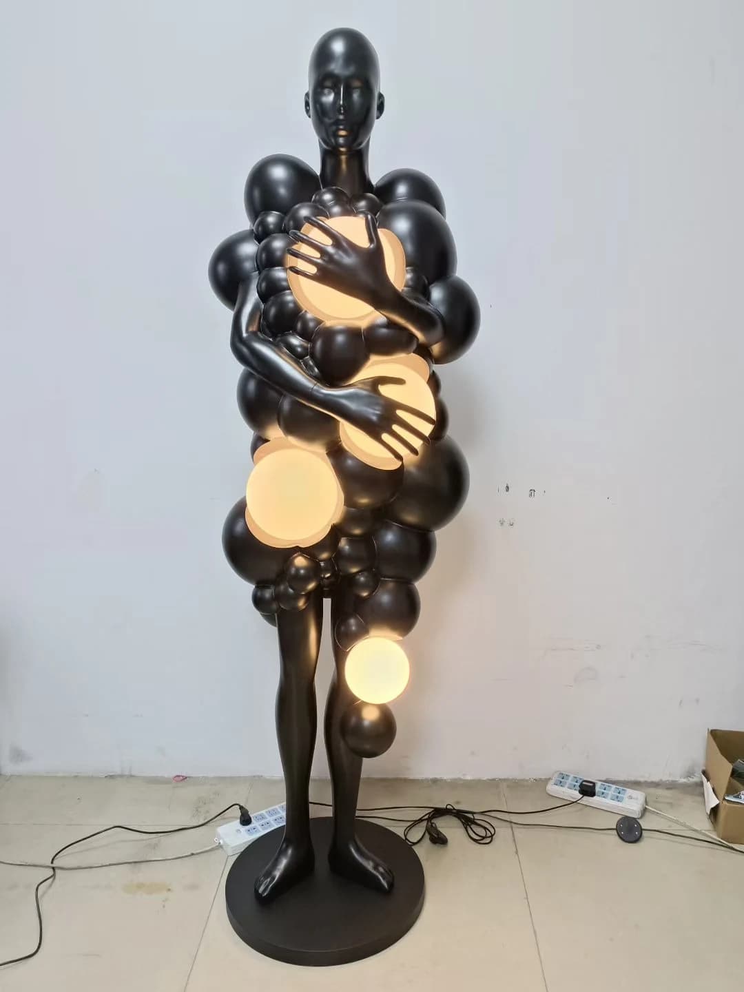 Escultura de figura negra abrazando globos de luz