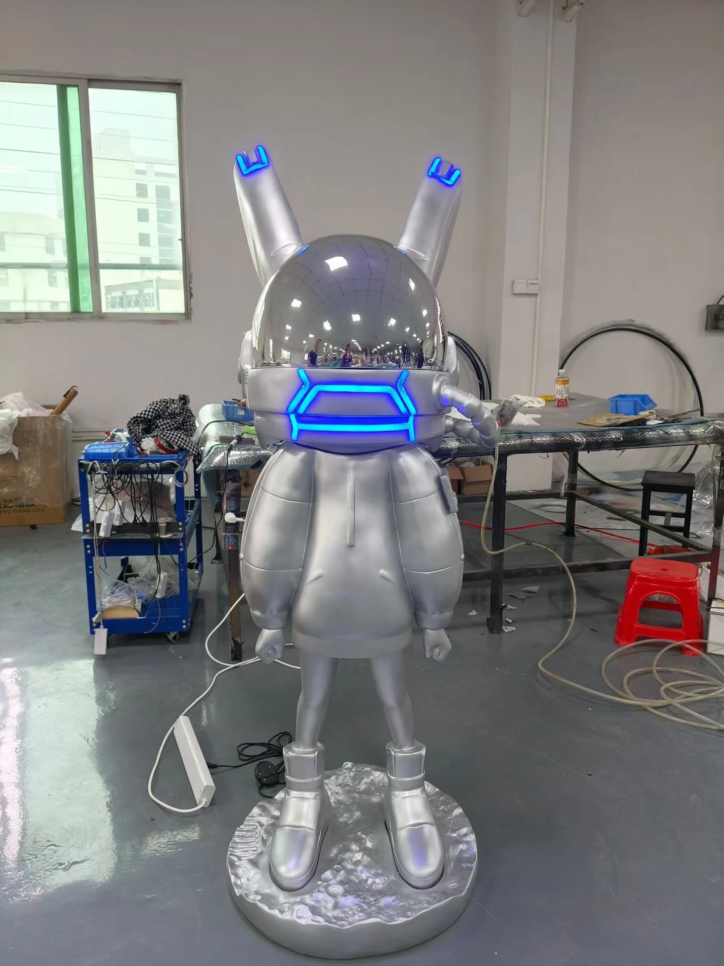 Escultura de conejo astronauta plateado con casco iluminado