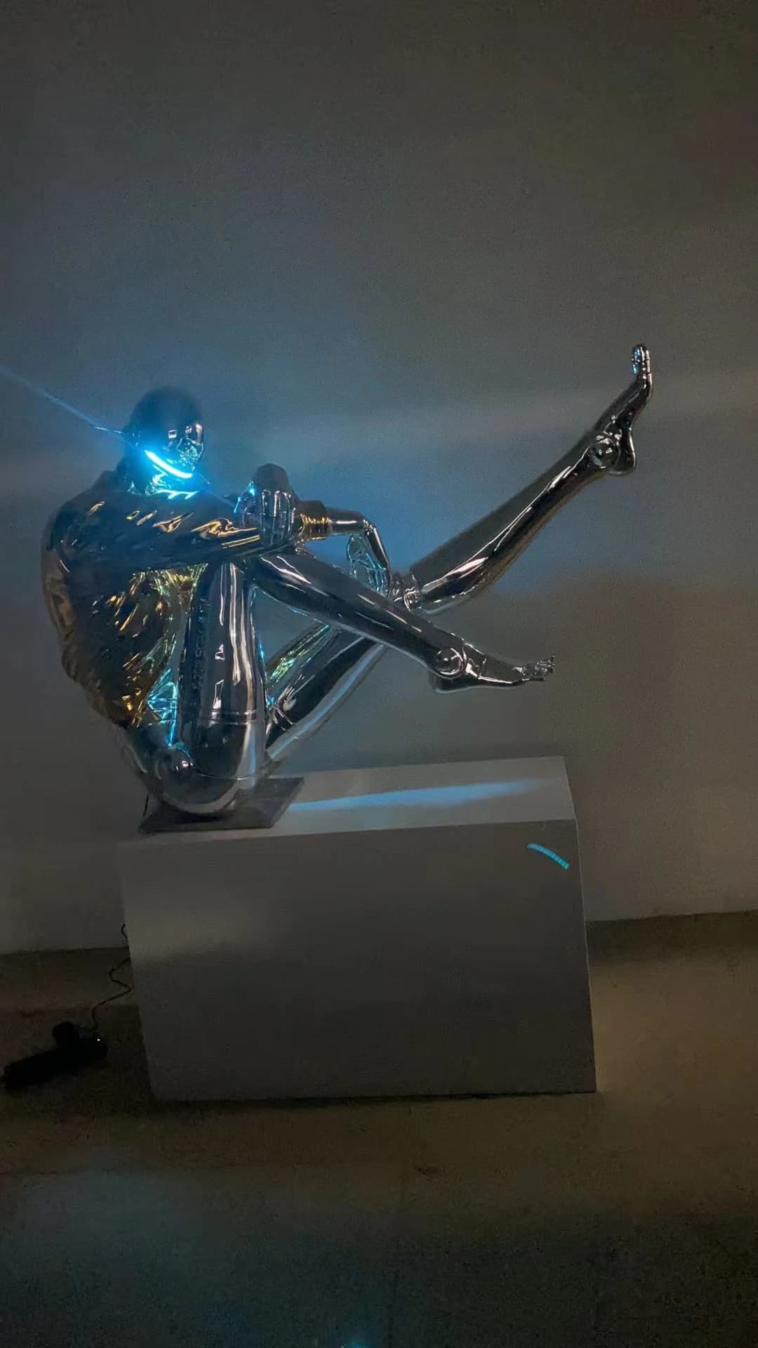 Escultura de figura plateada sentada con luz